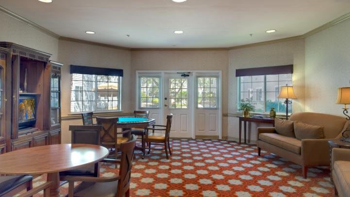 A cozy lounge area with tables, chairs, and large windows.