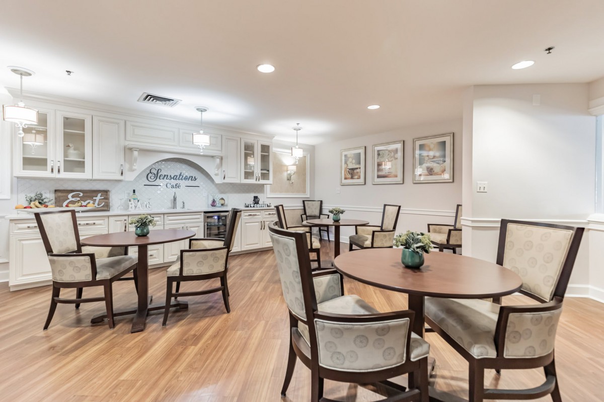 A modern kitchen and dining area with round tables and upholstered chairs on wooden flooring.