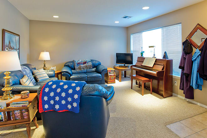 A cozy living room featuring leather couches, a piano, and a television.