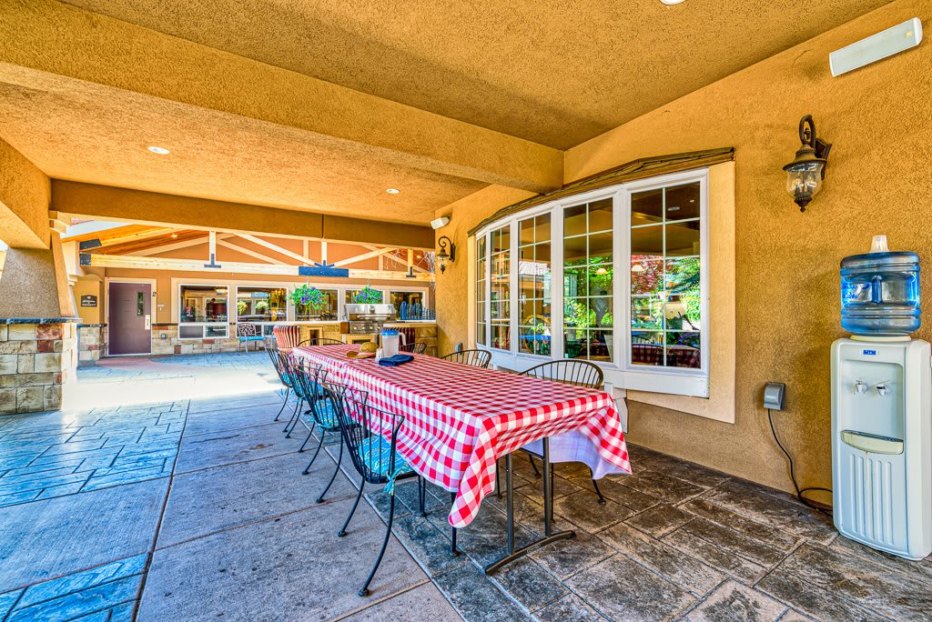 A spacious outdoor patio with a long, checkered-tablecloth-covered table and chairs.