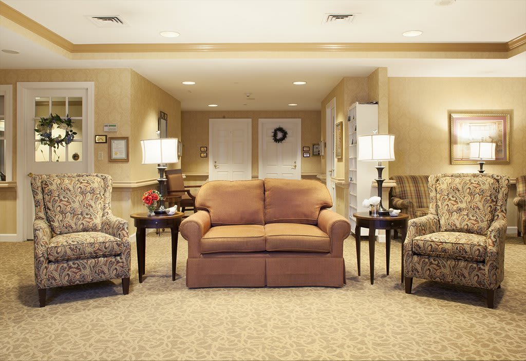 A cozy living room with a central couch, two armchairs, side tables, and lamps.
