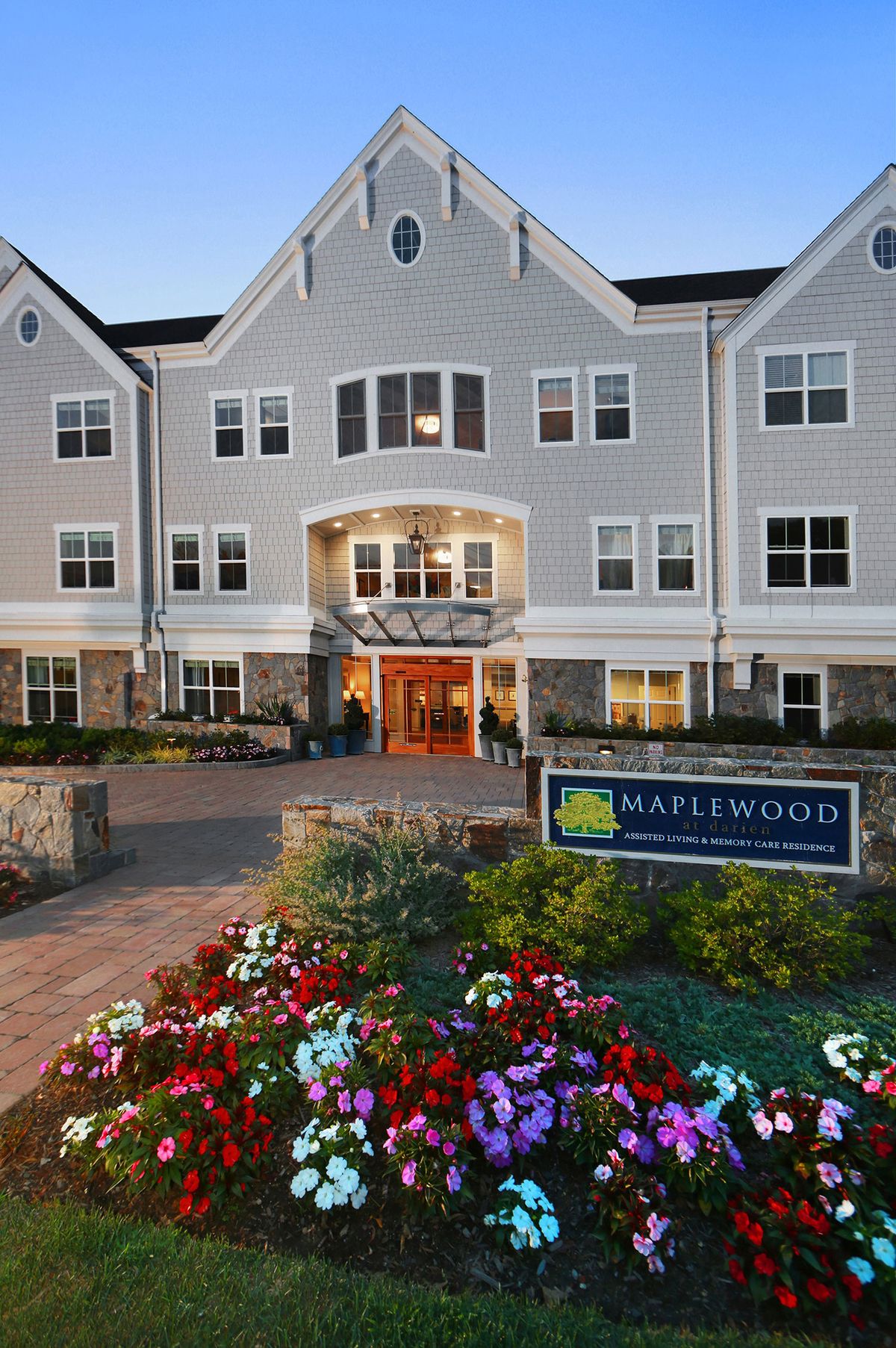 A front view of a building with an entrance, surrounded by well-maintained landscaping and colorful flowers.