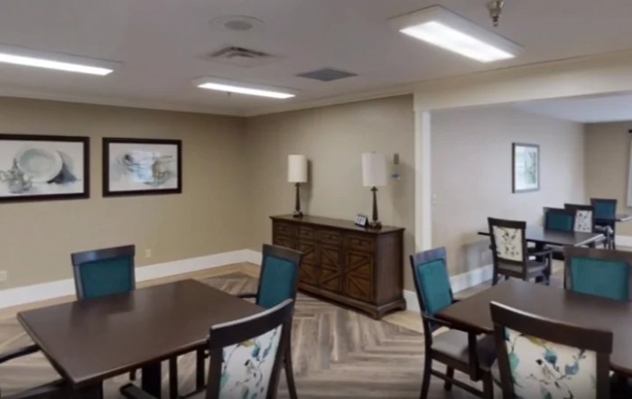 A modern dining room with tables and chairs, decorated with artwork and ambient lighting.