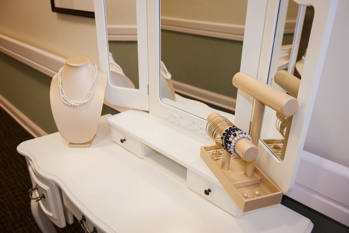 A jewelry display featuring a necklace stand and bracelet holder arranged on a white table with mirrors.