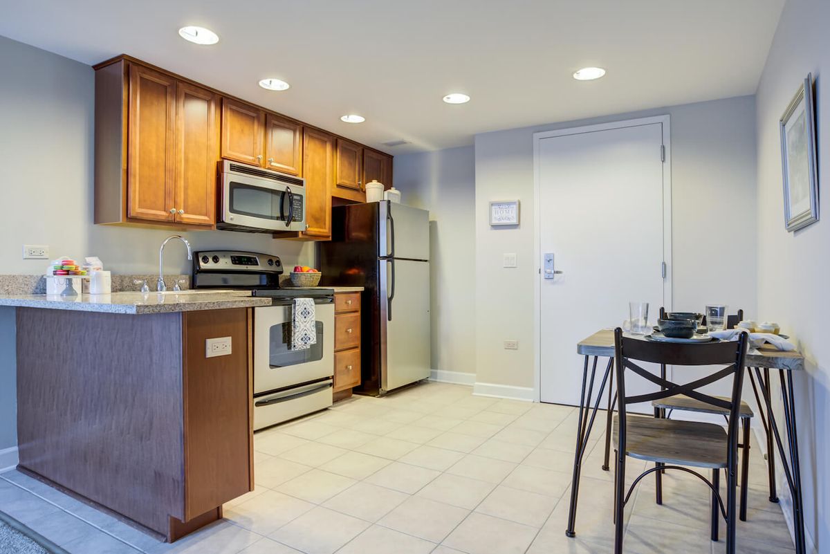 A modern kitchen with stainless steel appliances and wooden cabinets in an open-plan apartment.
