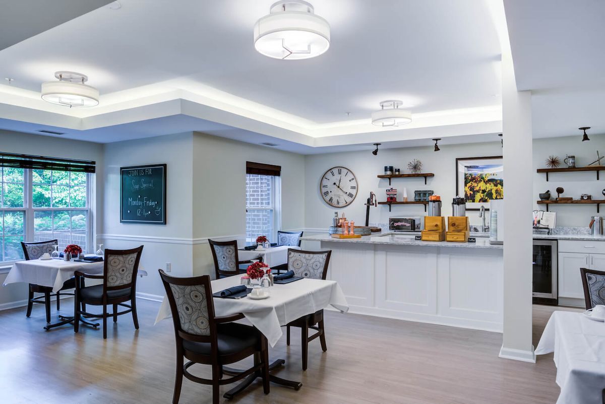 A modern dining area with elegant furniture and stylish decor, featuring a large clock and shelves on the wall.