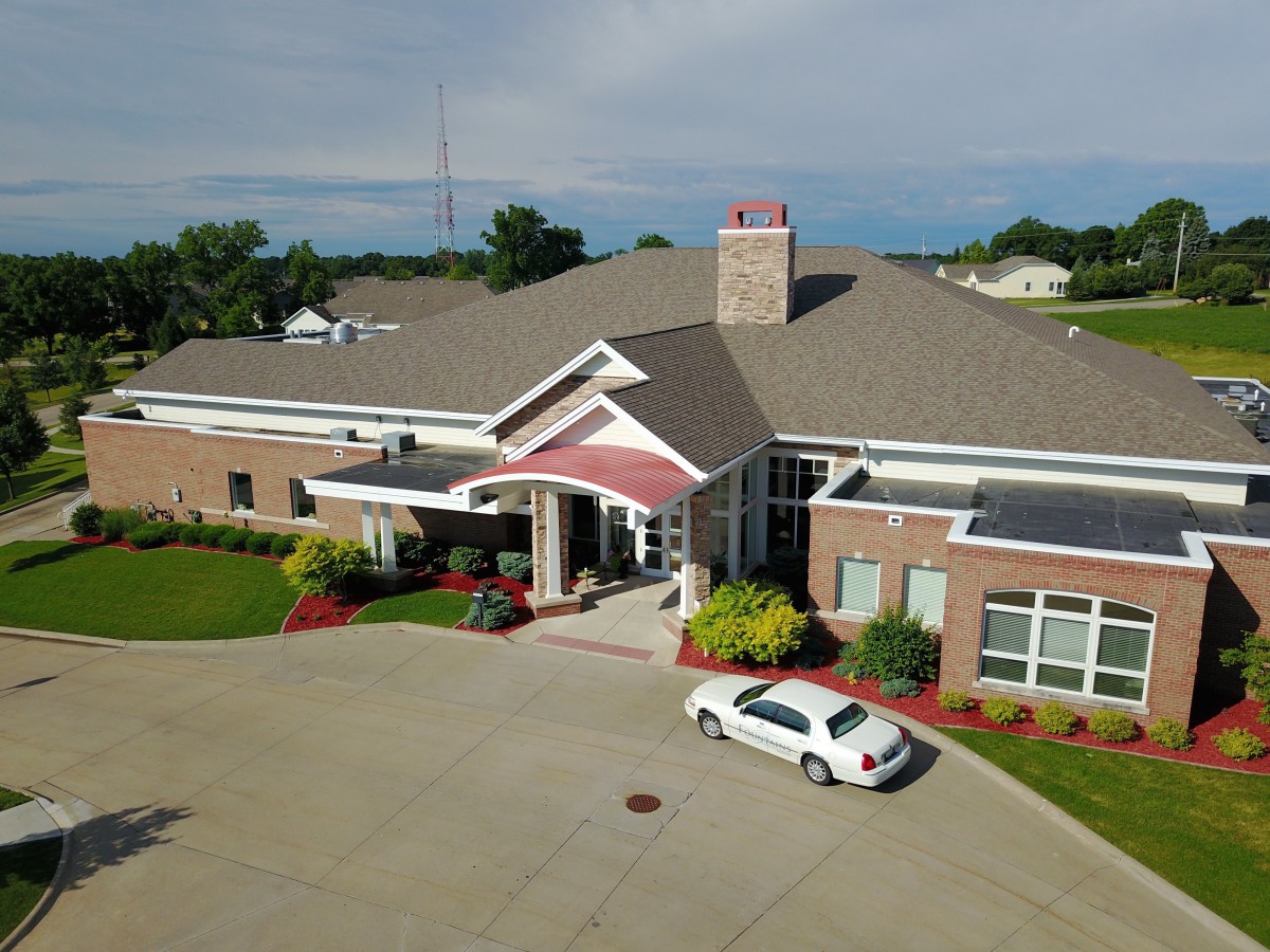 Aerial view of a building with a car parked in the driveway and landscaped surroundings.