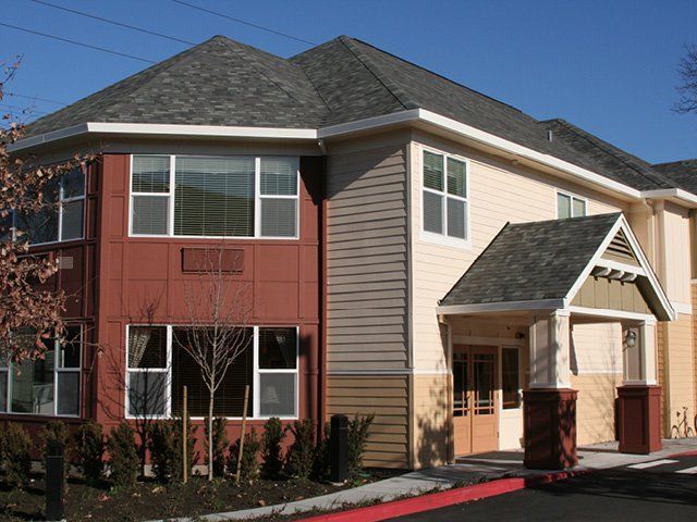 A modern residential building with mixed siding and multiple windows.