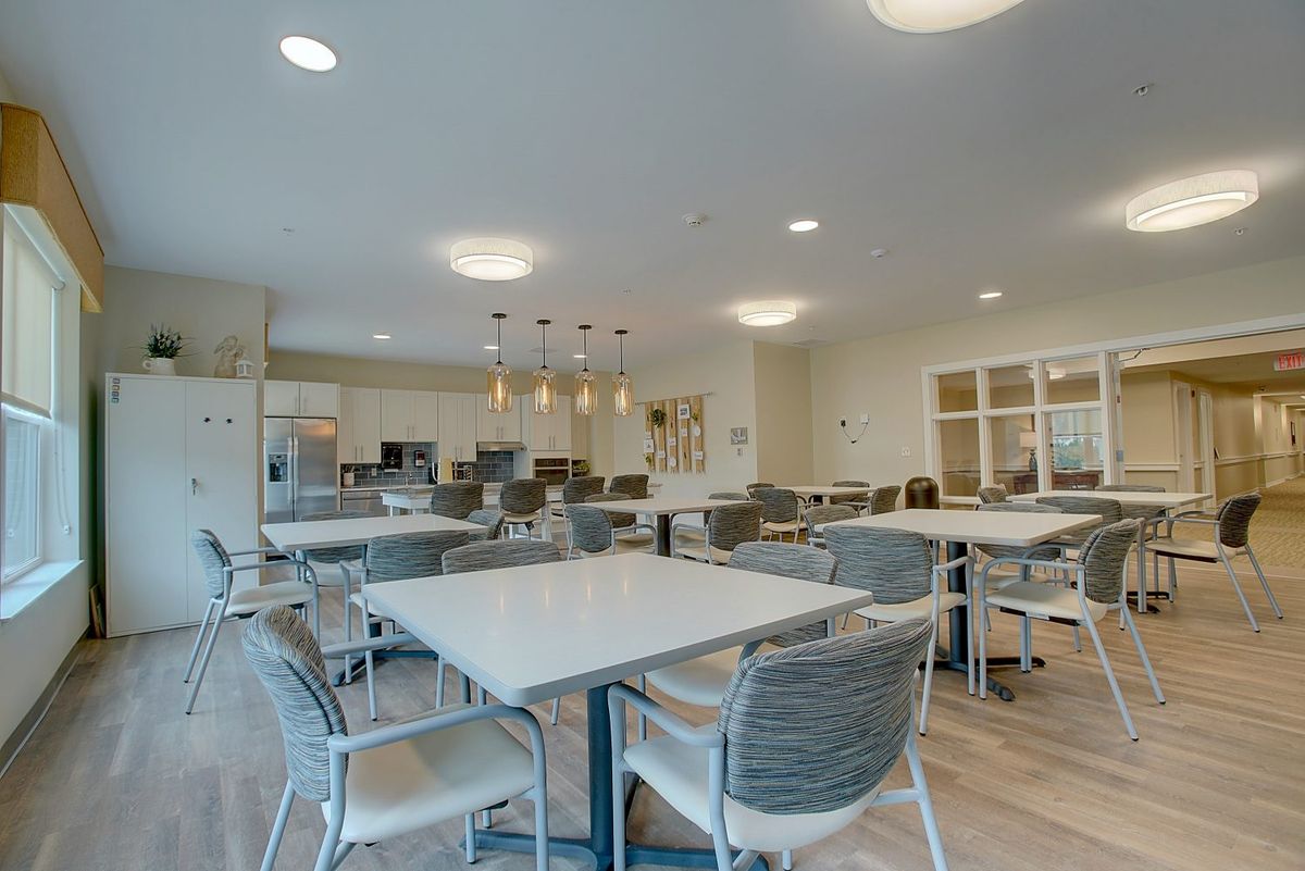 A modern dining area with an open kitchen, featuring contemporary tables and chairs.