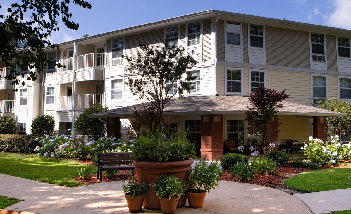A well-maintained residential apartment building surrounded by lush gardens.