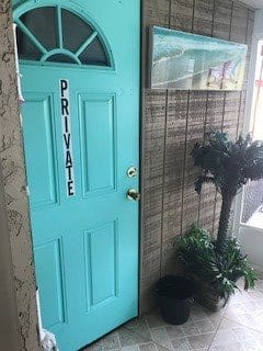 A turquoise door labeled 'Private' next to some indoor plants.
