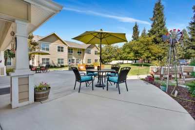 A spacious outdoor patio with a table, chairs, and an umbrella, set against a residential building.