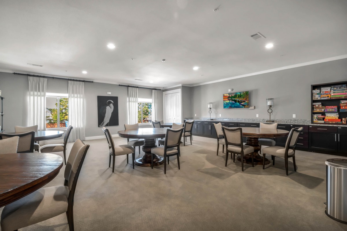 A spacious and modern dining area with multiple tables and chairs, featuring large windows and elegant artwork.