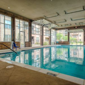 A modern indoor swimming pool with large windows and architectural design.