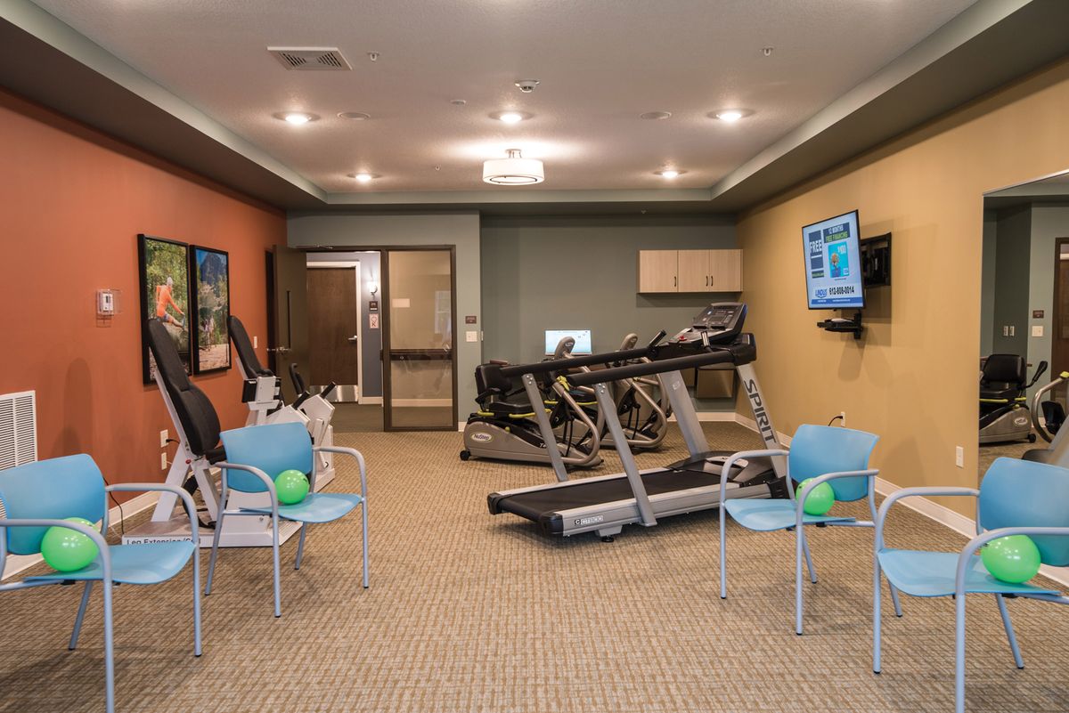 A small gym with treadmills, chairs, and a TV.