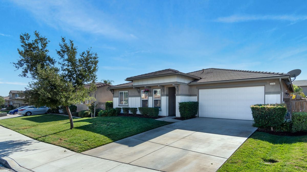A suburban single-story house with a well-kept front yard and a driveway leading to the garage.