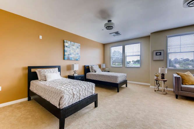 A modern bedroom with twin beds and neutral color scheme.
