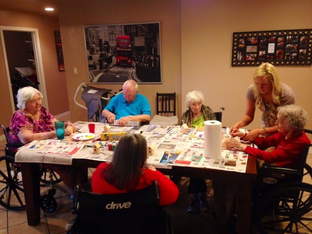 A group of seniors engaged in an art activity at a table indoors.