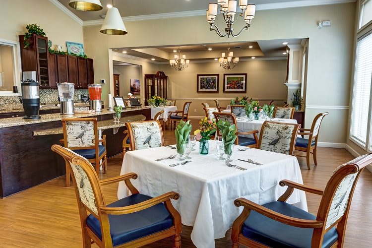 An elegant dining room with neatly set tables and comfortable chairs, featuring tasteful decor and ambient lighting.