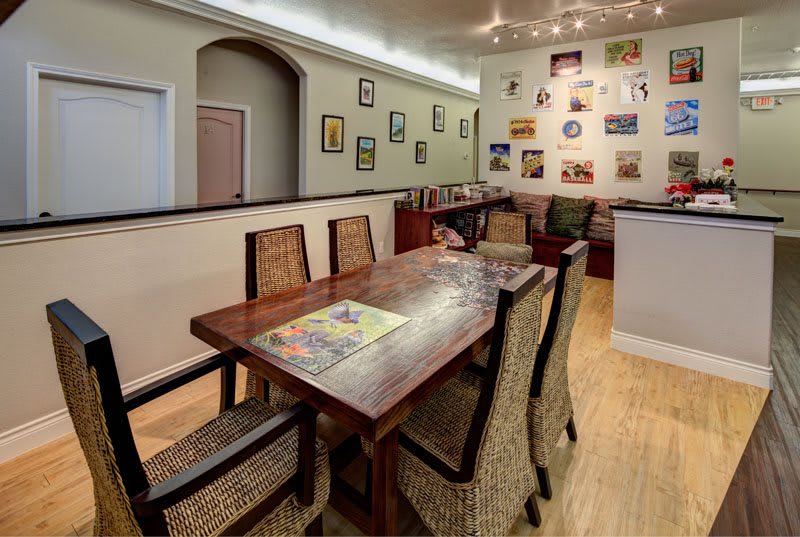 A cozy dining area with a wooden table and wicker chairs, adorned with a gallery wall of various artworks.