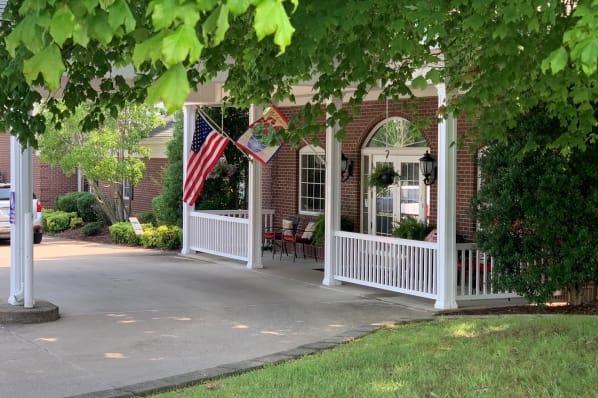 A charming house porch adorned with flags and surrounded by lush greenery.
