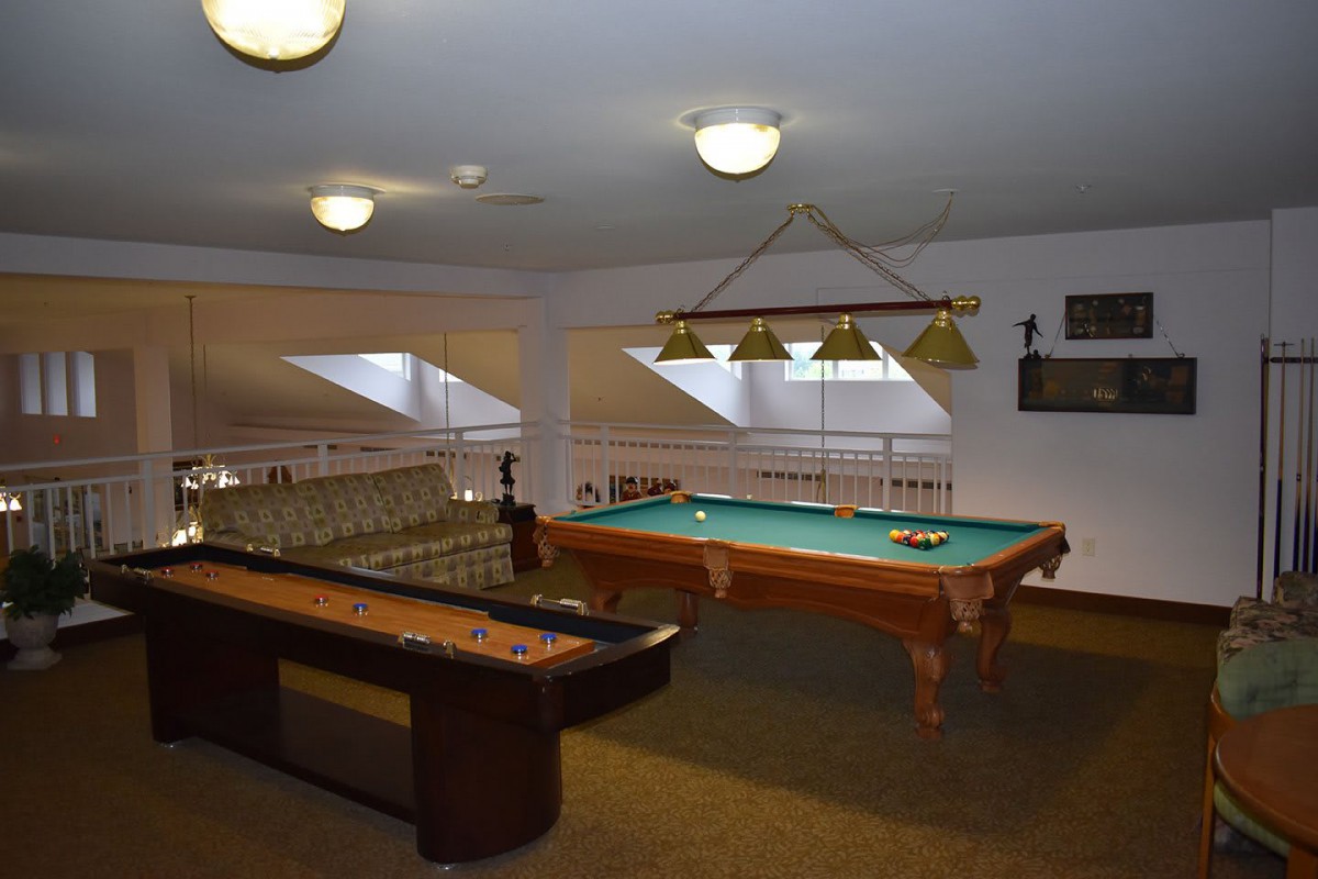 A cozy game room featuring a pool table and shuffleboard setup.