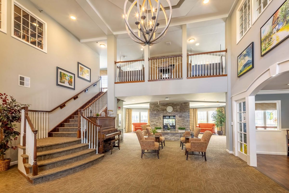 Spacious living room with elegant decor, featuring a grand staircase and modern chandelier.