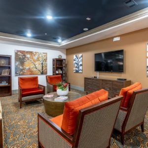 A modern living room with vibrant orange chairs and elegant artwork.