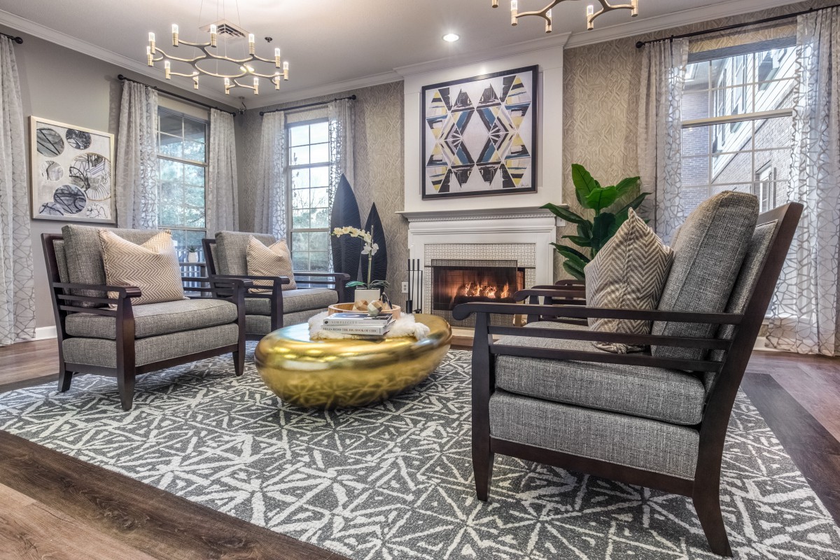 A modern living room featuring elegant armchairs, a central coffee table, and a cozy fireplace with decorative artwork above.