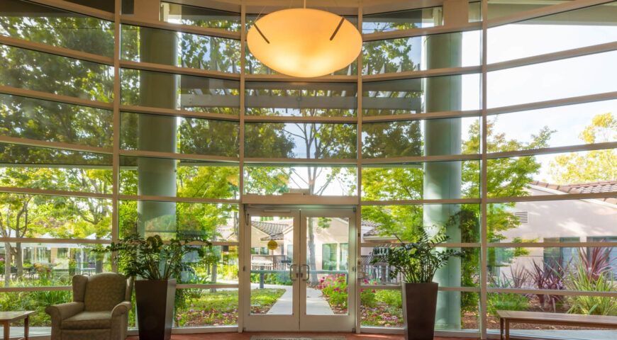 A modern building entrance with large glass windows and potted plants.