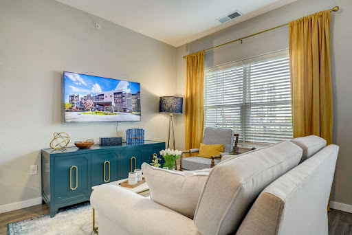 A stylish and cozy living room featuring a modern sofa, vibrant curtains, and a large television for entertainment.