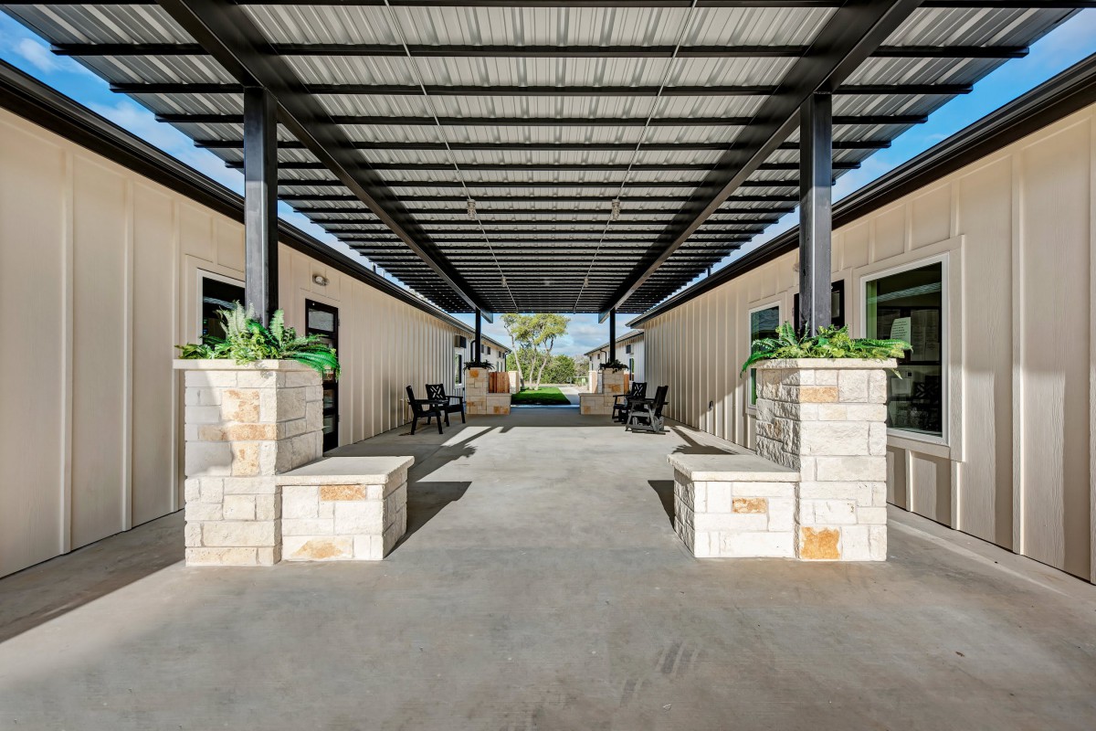 A modern outdoor covered corridor with benches and planters.