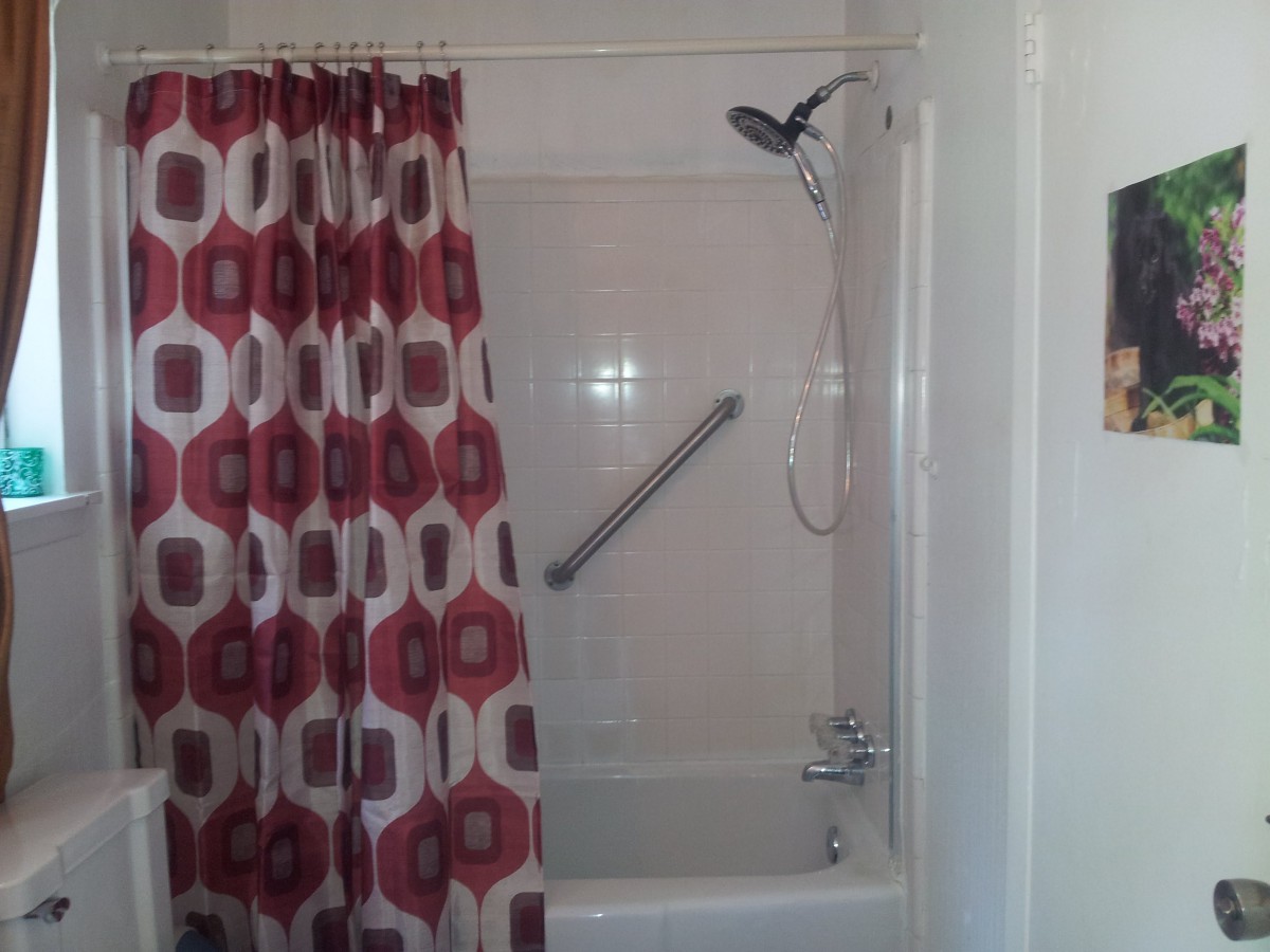 Bathroom featuring a bathtub with a red patterned shower curtain and a grab bar installed.