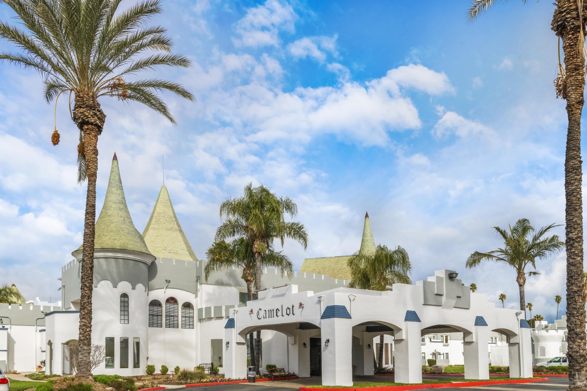 A whimsical castle-like building with turreted roofs and palm trees under a bright blue sky.