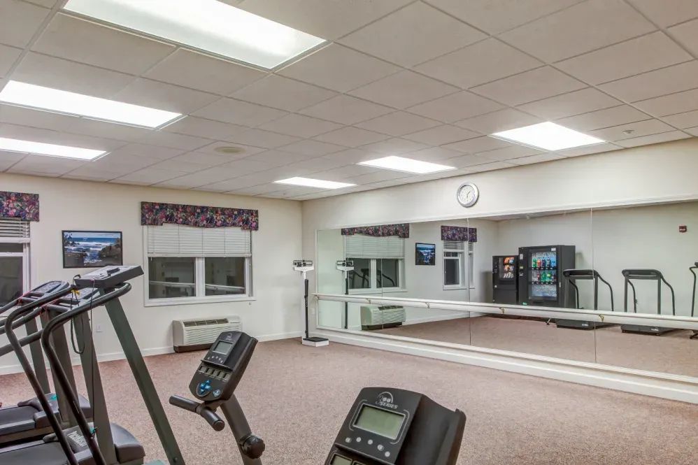 A gym with exercise equipment and mirrors on the walls.
