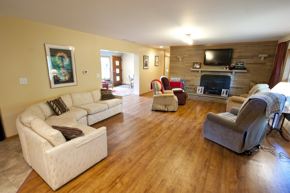 A cozy living room with multiple sofas, a fireplace, and a television set atop the mantle.