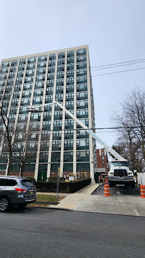 A maintenance truck positioned outside a high-rise building, equipped with an extended ladder for work on upper floors.