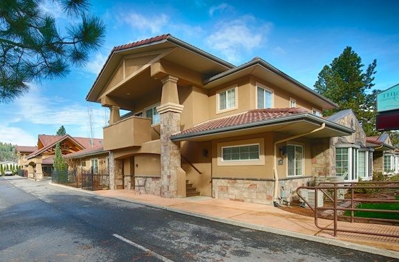 A modern two-story residential building with stone accents and a balcony.