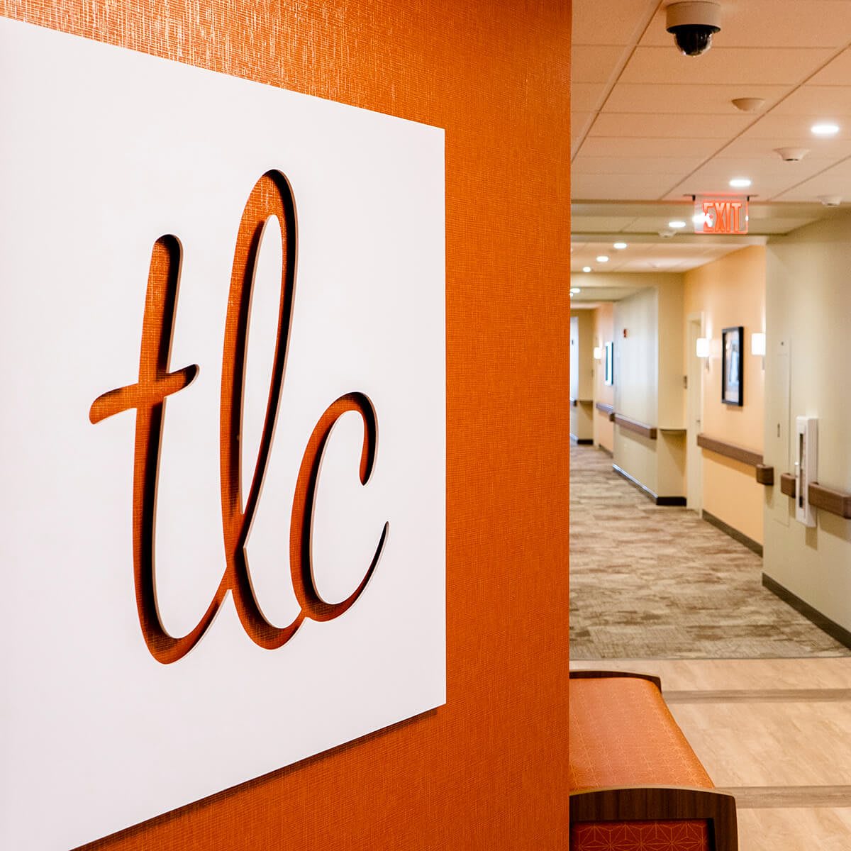 A modern hallway in a clinic featuring a stylish 'tlc' sign on the wall.