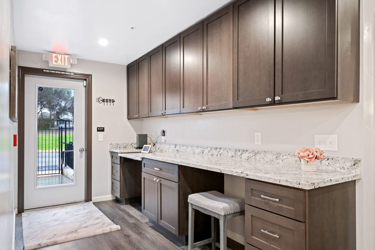 A modern kitchen interior with dark wood cabinets and a marble countertop.