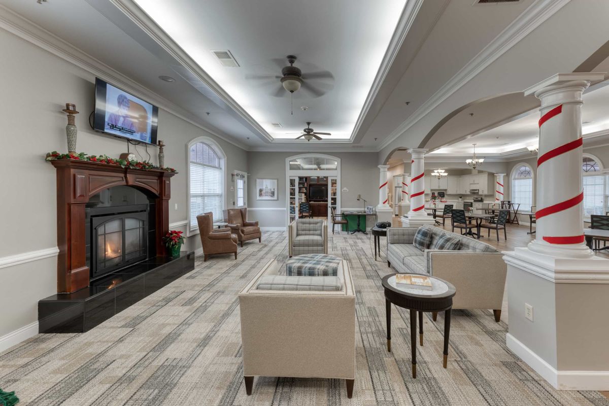 A cozy lounge area with comfortable seating, a fireplace, television, and bookshelves.