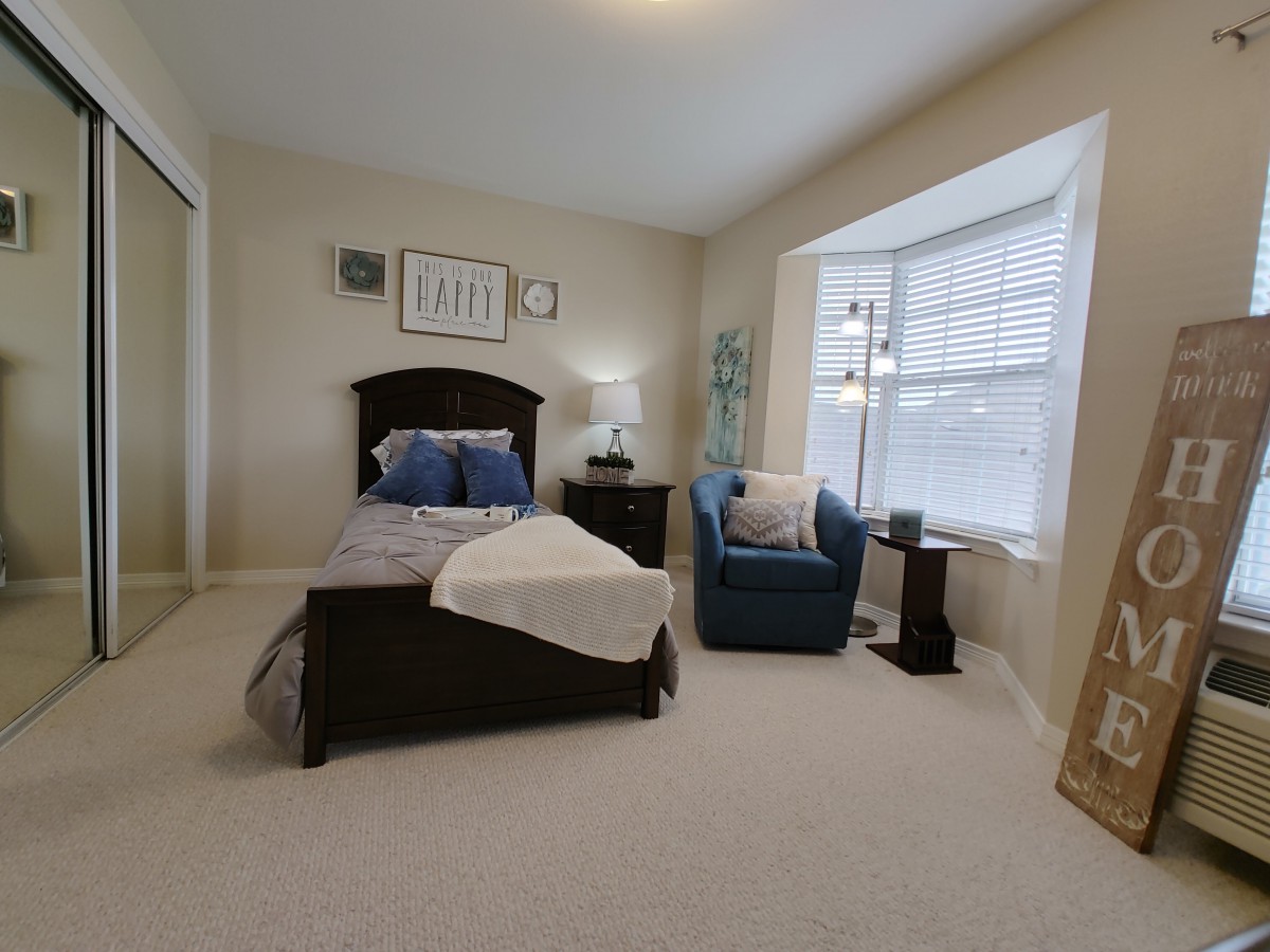 A cozy bedroom with a single bed and an armchair by the window.