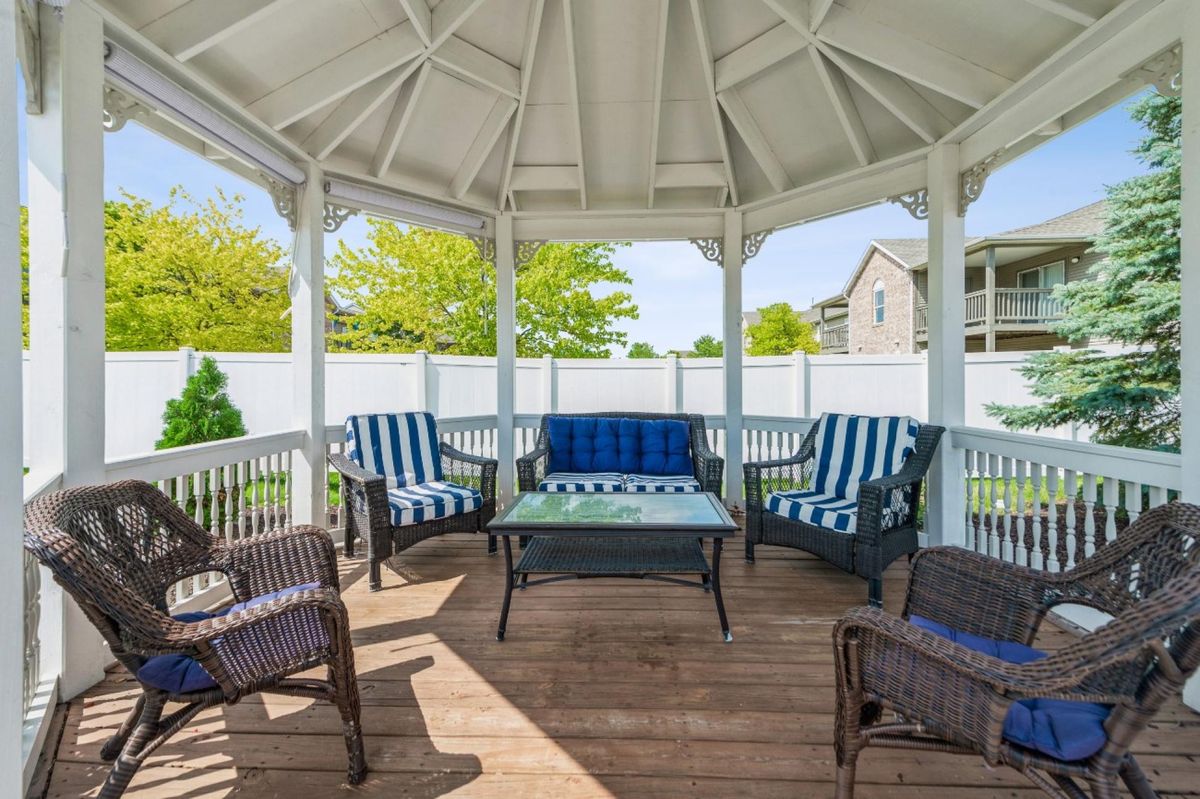 A cozy gazebo with comfortable outdoor seating in a sunny backyard.