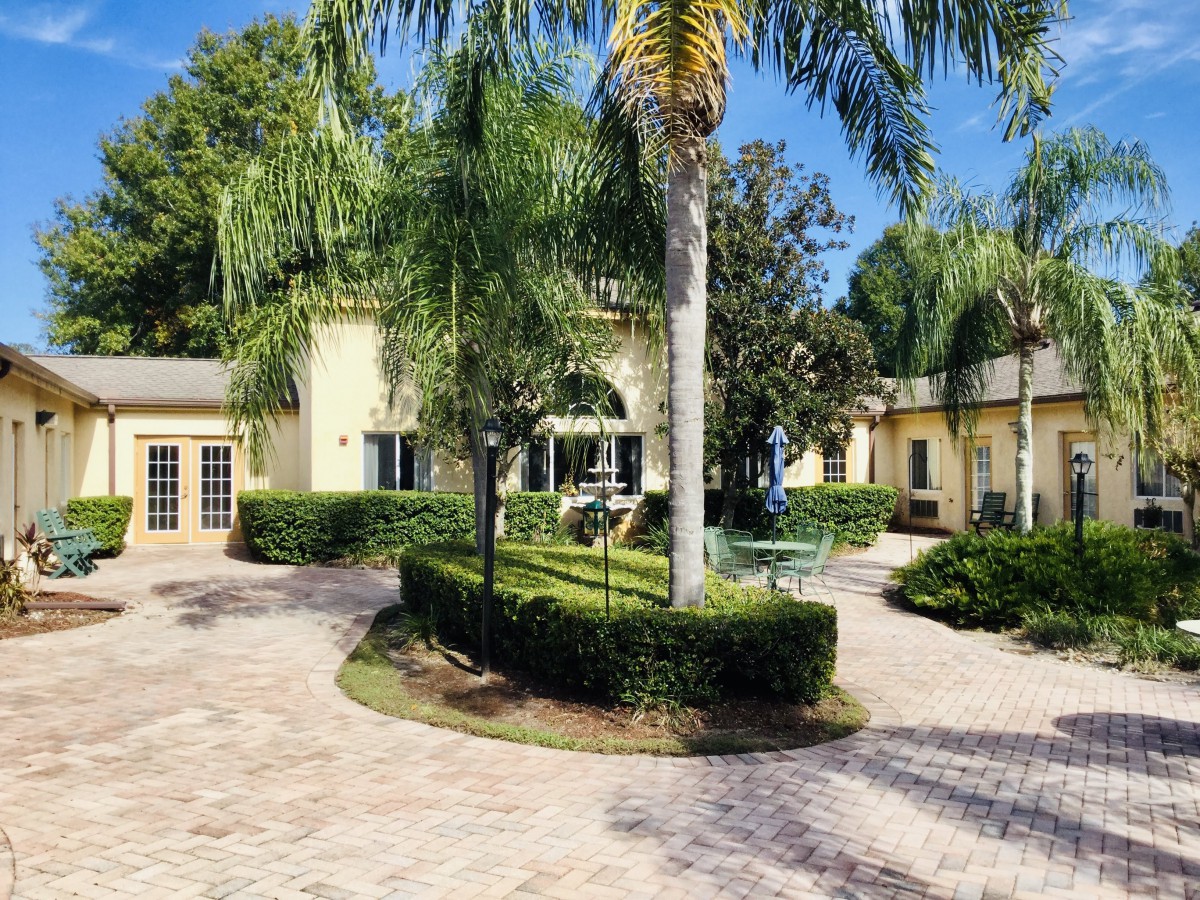 A luxurious house with a beautifully landscaped garden and palm trees.