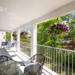 A sunlit patio with outdoor furniture and vibrant hanging plants.
