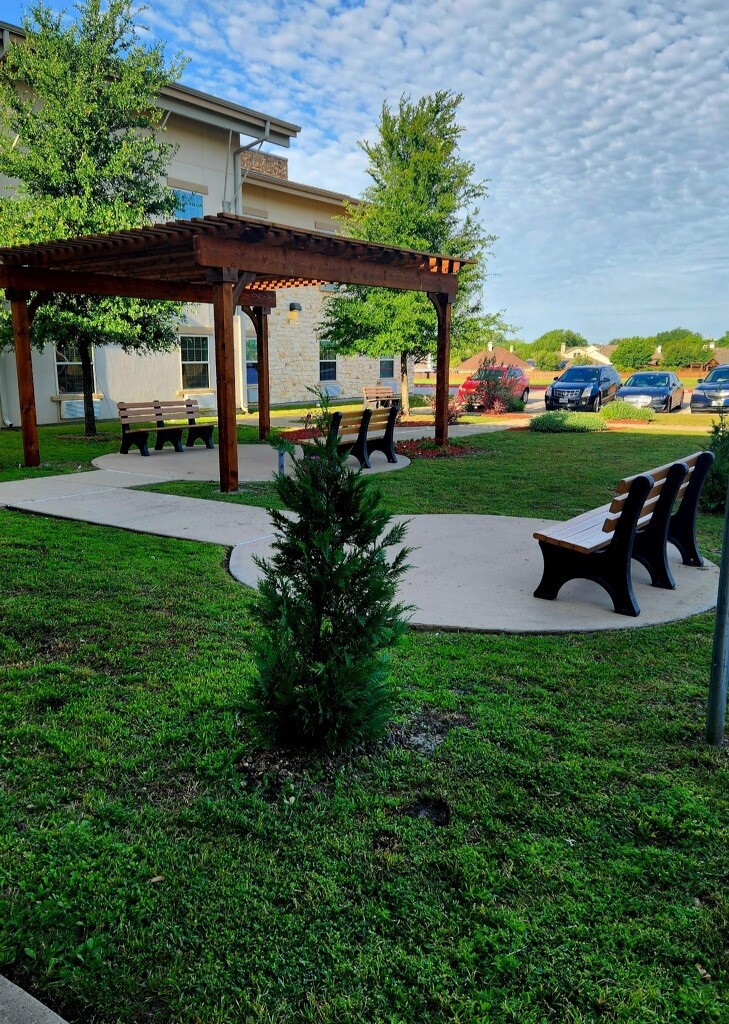 A serene outdoor garden area with benches and a pergola, surrounded by greenery.