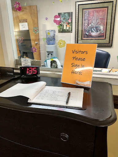 A visitor check-in desk with a sign requesting guests to sign in.