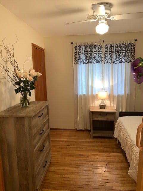 A cozy bedroom with wooden furniture, a bed, and decorative floral arrangements.