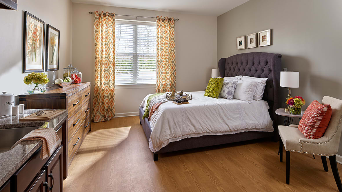 A cozy bedroom with a neatly made bed, patterned curtains, and stylish decor.