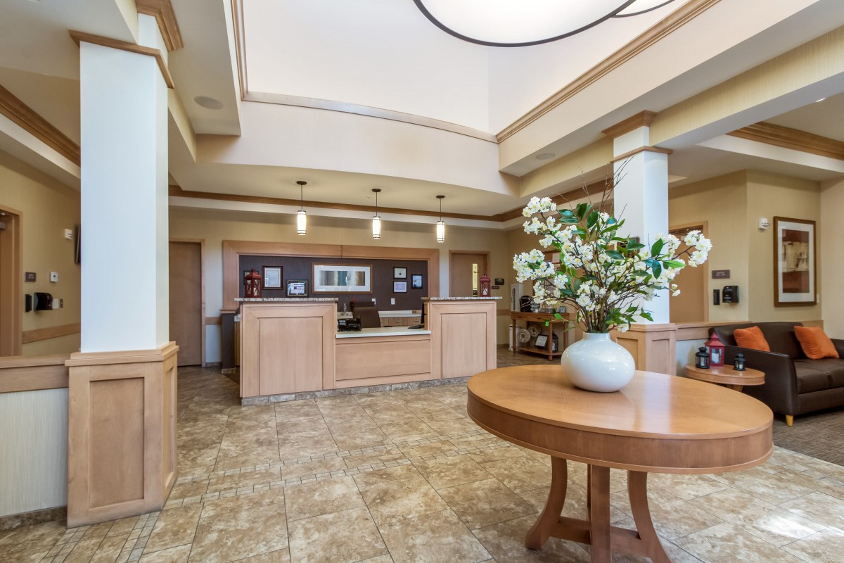 A well-lit lobby area featuring a reception desk and a round table with a floral arrangement.